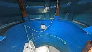 Een kleine, afgesloten badkamer met een wit toilet en een blauw interieur.
