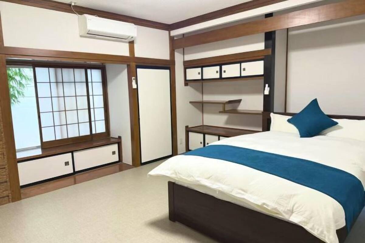 A bedroom with a bed, built-in storage, and a sliding door with a view.