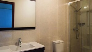 Ein Badezimmer mit Waschbecken, Spiegel, Toilette und Duschkabine.