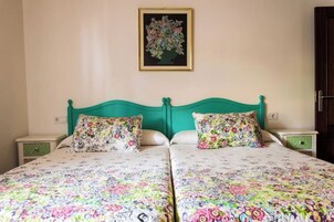 Una cama doble con ropa de cama floral, cabecera verde y una obra de arte floral enmarcada en la pared.