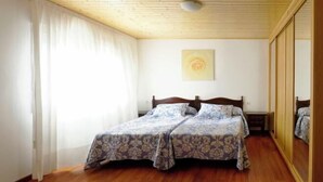 Ein Schlafzimmer mit Holzboden, einem Bett mit Blumenmuster-Bettwäsche, einem Spiegel und einem Bild an der Wand.