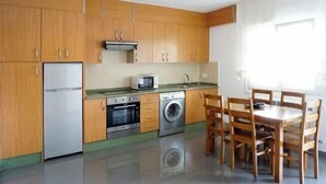 Eine kompakte Küche mit Holzausstattung, einer Mikrowelle, einem Backofen und einer Waschmaschine.