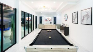 A modern living room with a pool table, a sofa, and a TV. - The Moment Pool Villa (Sattahip)