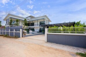 A modern two-story house with a covered driveway, a gated entrance, and a swimming pool. - The Moment Pool Villa (Sattahip)