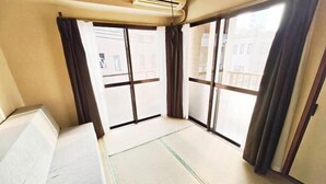 A room with tatami mats, sliding doors, and a view of buildings outside. - SUMMERSONG (Tokyo)
