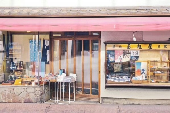 Une devanture de magasin avec un auvent rose, une porte en bois et des vitrines.
