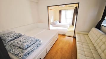 A bedroom with a bed, a sofa, and a mirror.