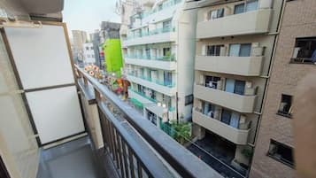 A multi-story residential building with balconies, a green awning, and a view of the street below.