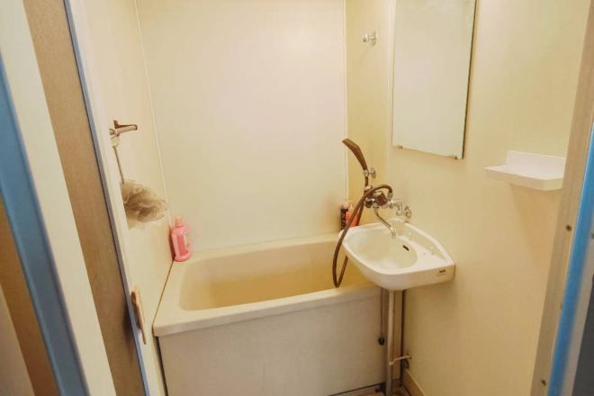 A small bathroom with a bathtub, a sink, and a mirror.