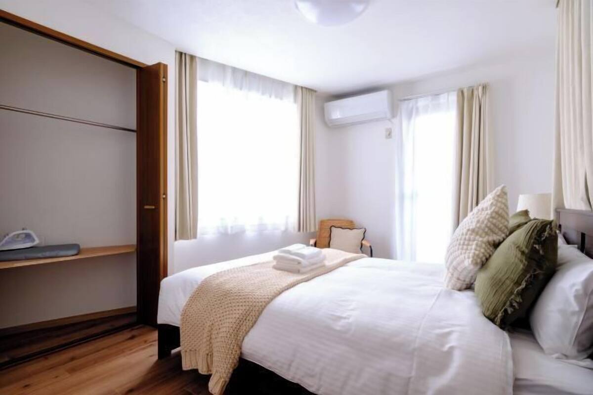 Un dormitorio con cama, armario y ventana.