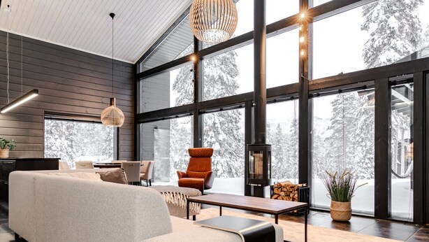 Un salon moderne avec une grande fenêtre, un canapé, un fauteuil, une table et une chemin ée.