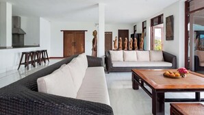 A modern living room with a dark wicker sofa, a light-colored sofa, and a wooden coffee table with fruits. - Pra Nang (Phuket)