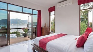 A bedroom with a large bed, a view of the sea, and a balcony with a potted plant. - Pra Nang (Phuket)