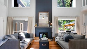 Un salón espacioso con dos sofás grises, una mesa de centro negra y una chimenea.