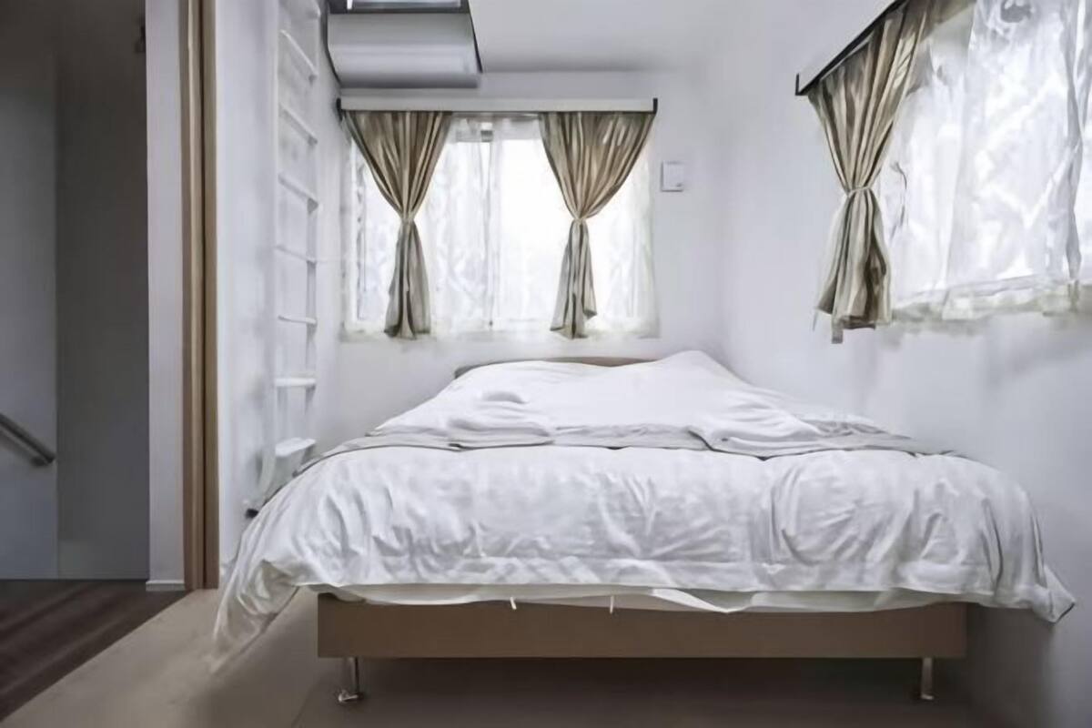 A bedroom with a bed, curtains, and a window.