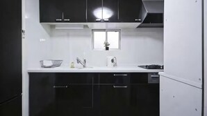 A modern kitchen with black cabinets, a white countertop, and a window above the sink. - 3BR - Shinjuku area, 5mins from station (Tokyo)