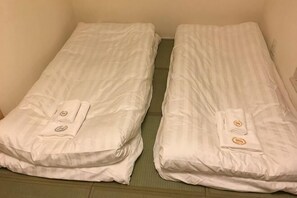 Two single beds with pillows and a folded blanket, a green floor, and a plain wall. - 3BR - Shinjuku area, 5mins from station (Tokyo)