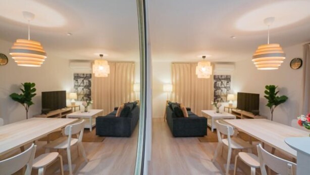 Un espace de repas moderne avec un canapé central, des chaises blanches et des luminaires suspendus.
