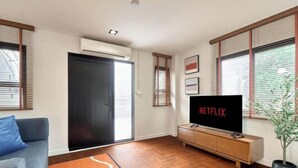 A modern living room with a sofa, a TV, and a wooden floor. - Emily Home 3BR Old Town Chiang Mai by Beginning With (Chiang Mai)
