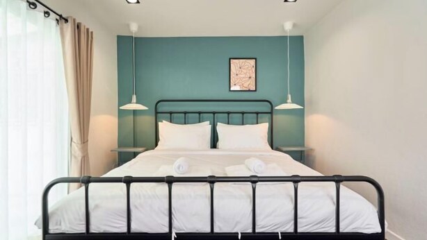 A bed with white linens, a teal wall, and two pendant lights. - Emily Home 3BR Old Town Chiang Mai by Beginning With (Chiang Mai)