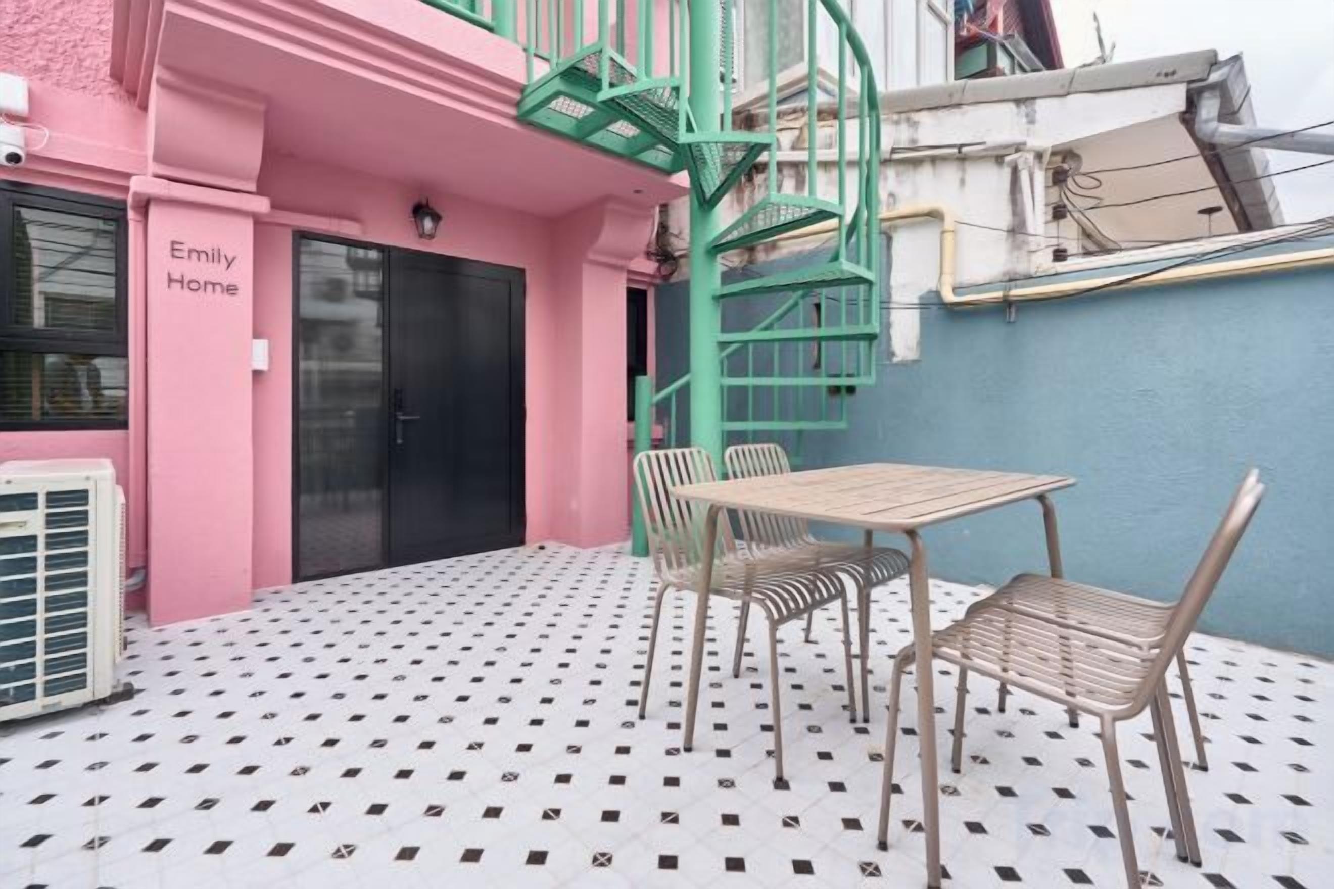 A pink building with a staircase, a table with chairs, and a patterned floor.