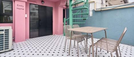A pink building with a staircase, a table with chairs, and a patterned floor.