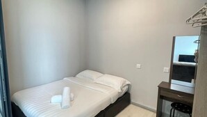 A small, neatly made room with a bed, a desk, and a mirror. - Jesselton Quay Central Citypad (Kota Kinabalu)
