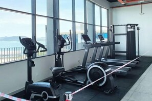 A gym with cardio machines, a weight bench, and a view of the sea. - Jesselton Quay Central Citypad (Kota Kinabalu)
