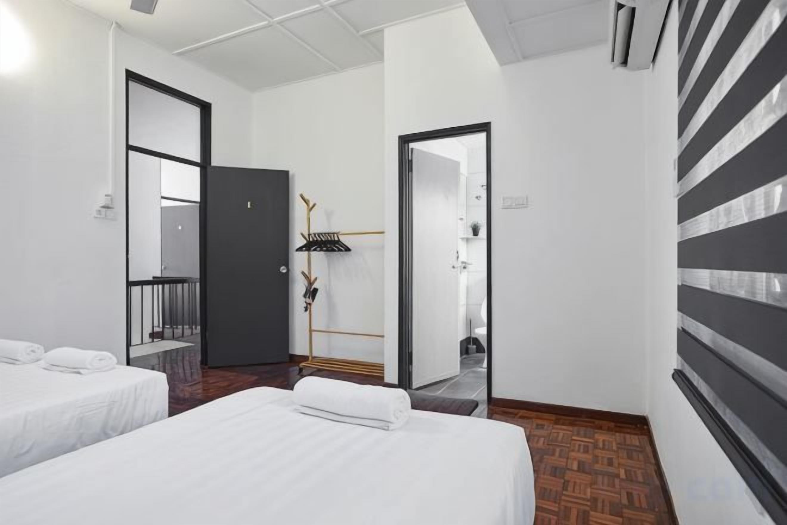 Habitación de hotel con dos camas, un espejo, una puerta que da a un balcón y una pared a rayas.
