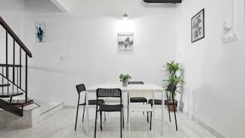 A dining area with a white table, black chairs, and a potted plant.