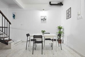 A dining area with a white table, black chairs, and a potted plant. - IpohGarden Homestay, 4-12pax 10mins to attraction (Ipoh)