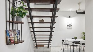 A staircase with a metal railing, a dining area with a table and chairs, and a potted plant. - IpohGarden Homestay, 4-12pax 10mins to attraction (Ipoh)
