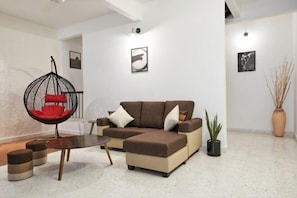 A modern living room with a sectional sofa, a hanging chair, a coffee table, and a potted plant. - IpohGarden Homestay, 4-12pax 10mins to attraction (Ipoh)