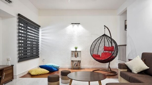 A modern living room with a hanging chair, a sofa, a coffee table, and a bookshelf. - IpohGarden Homestay, 4-12pax 10mins to attraction (Ipoh)