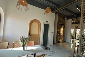 Een modern interieur met een witte tafel, rieten stoelen en een houten deur.