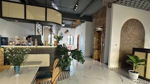 Un área de recepción con mostrador, asientos, plantas en macetas y un diseño interior moderno.