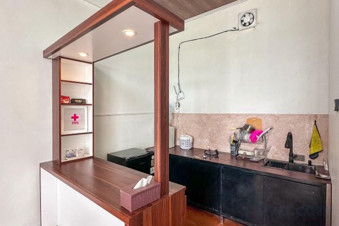 A reception area with a wooden counter, a mirror, and a shelf with a first aid kit.
