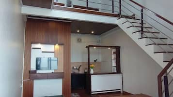 A modern interior with a staircase, a kitchen area, and a seating area.