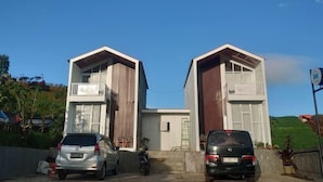 A modern building with two separate units, each featuring a balcony and a garage. - Skypiea dieng (Batur)
