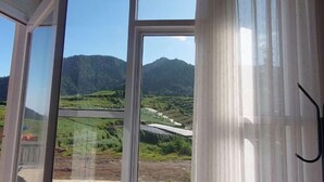 A room with large windows offering a view of a mountainous landscape. - Skypiea dieng (Batur)
