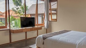 A bedroom with a bed, a TV on a wooden stand, and a window with a view of houses and greenery. - 2 Bedroom Villa Avyathi (Bali)