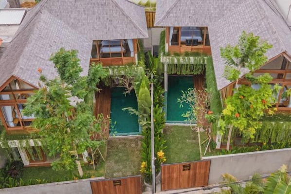 A house with a sloped roof, wooden windows, and a garden with various plants.