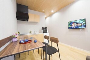 Uma cozinha moderna com área de refeições, uma TV fixada na parede e teto de madeira.