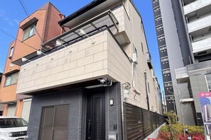 Un immeuble à plusieurs étages doté d’un portail de garage, d’un balcon et surplombant un ciel dégagé.
