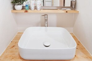 A white rectangular sink with a single faucet, a wooden shelf above it, and a potted plant to the left. - Sumiyoshinoyado (Osaka)