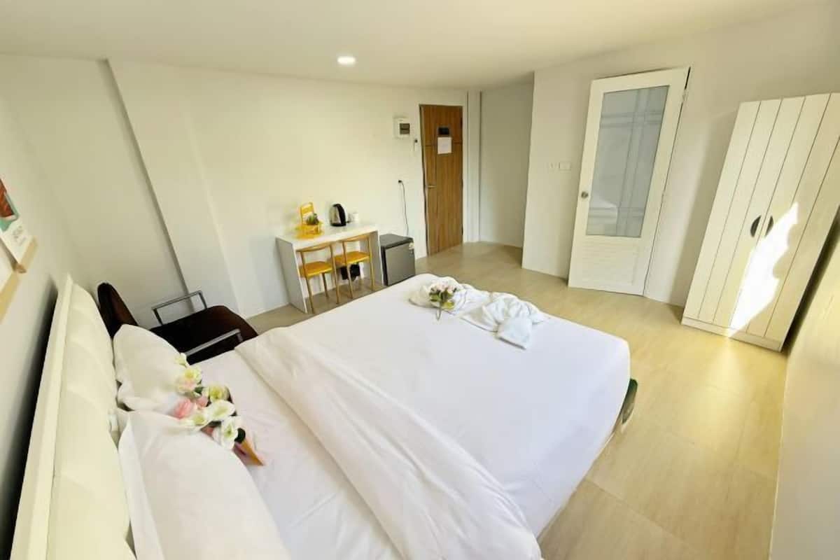 A hotel room with a bed, a desk, a chair, and a wardrobe.