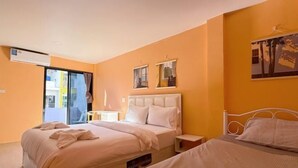 A hotel room with two beds, a window with a view, and a wall-mounted air conditioner. - Chen inn Boutique House Patong (Phuket)