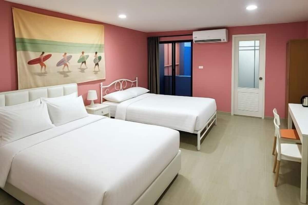 A hotel room with two beds, a desk, a chair, a window, and an air conditioning unit.