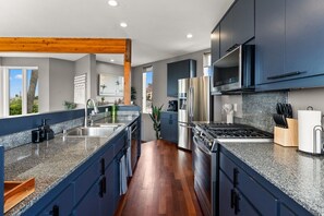 Una cocina moderna con armarios oscuros, encimeras de granito, electrodomésticos de acero inoxidable y vigas de madera.