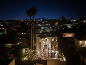 Un edificio moderno de varios pisos con un área exterior bien iluminada, que incluye una escalera y asientos.